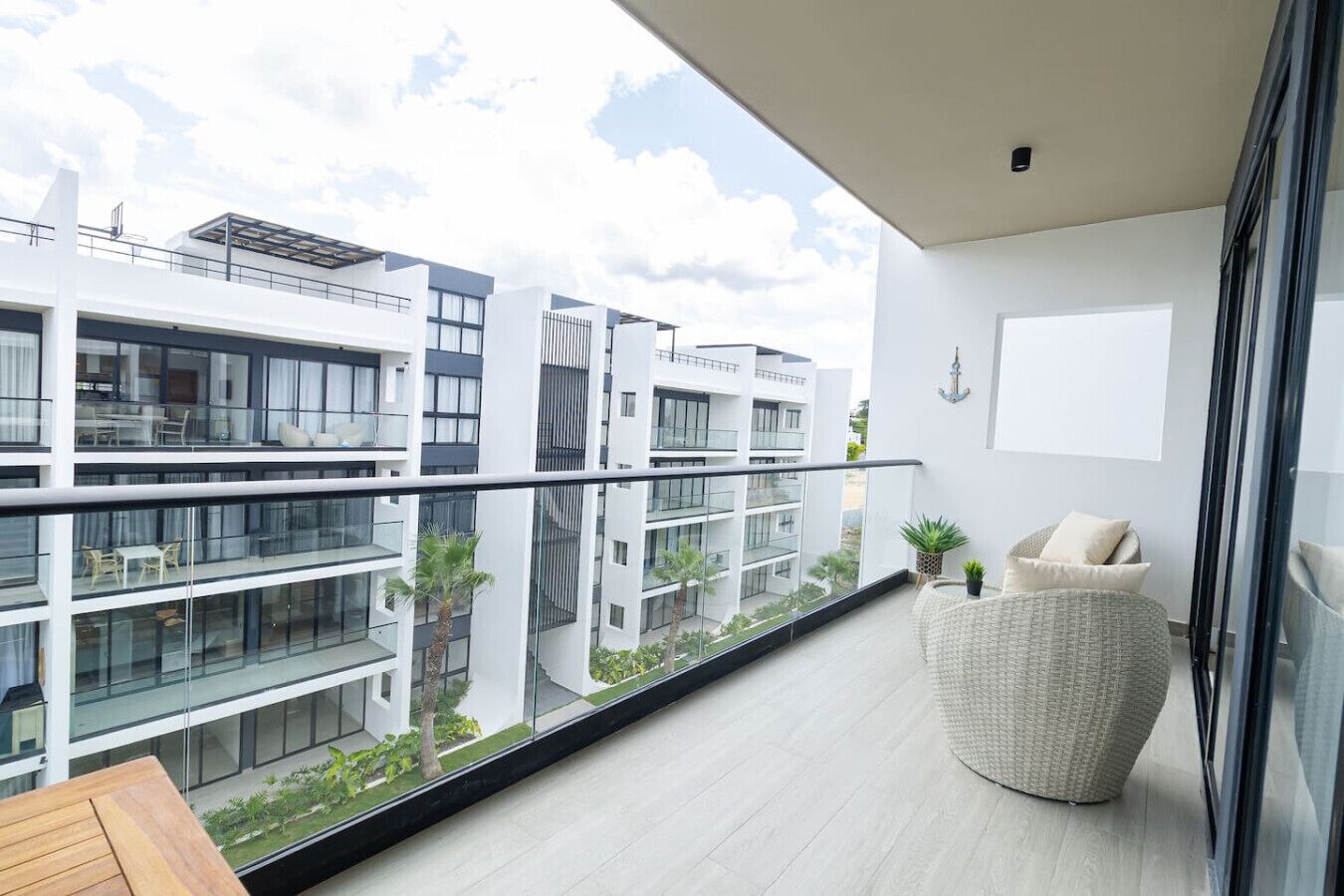 A modern apartment with a balcony, large windows, and a view of neighboring buildings.