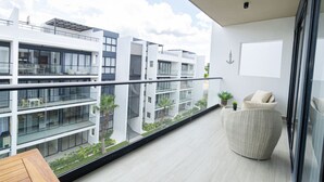 A modern apartment with a balcony, large windows, and a view of neighboring buildings. - Spacious 3BD Penthouse Private Rooftop Sea Breeze (San Rafael del Yuma)
