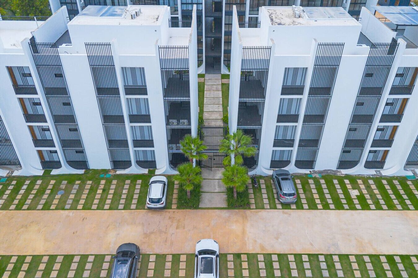 A modern multi-story building with a symmetrical facade, featuring balconies and a central walkway.