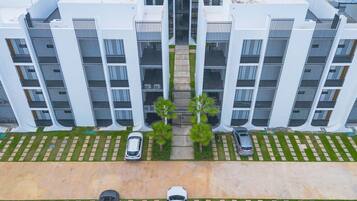 A modern multi-story building with a symmetrical facade, featuring balconies and a central walkway.