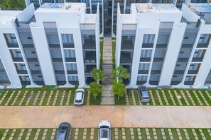 A modern multi-story building with a symmetrical facade, featuring balconies and a central walkway.