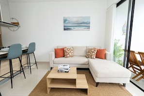 A modern living room with a sofa, coffee table, and chairs. There is a bookshelf and a painting on the wall. - Spacious 3BD Penthouse Private Rooftop Sea Breeze (San Rafael del Yuma)