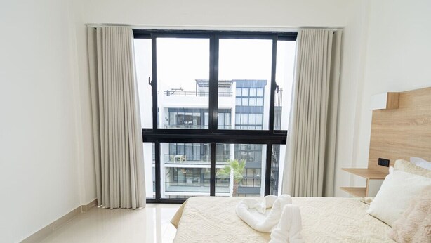 A hotel room with a large window, a bed with white linens, and a wooden headboard. - Spacious 3BD Penthouse Private Rooftop Sea Breeze (San Rafael del Yuma)