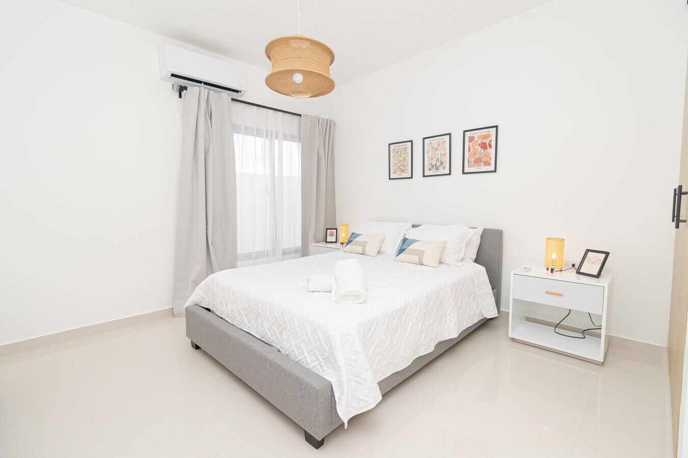A modern bedroom with a large bed, a bedside table, and a hanging light fixture.