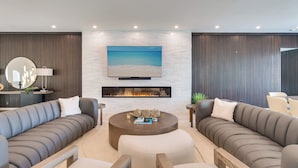 A modern living room with a fireplace, two sofas, a coffee table, and a TV mounted on the wall. - Naples Waterfront 3 Master en-suites Pool Boat lift (Naples)