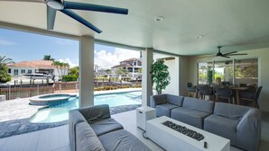 A modern outdoor living area with a pool, grey sofas, a white coffee table, and ceiling fans. - Naples Waterfront 3 Master en-suites Pool Boat lift (Naples)