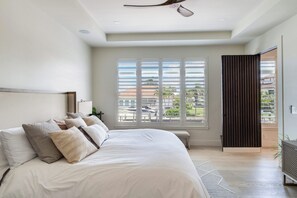 A bedroom with a bed, a ceiling fan, a window with blinds, and a view of buildings outside. - Naples Waterfront 3 Master en-suites Pool Boat lift (Naples)