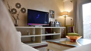 A living room with a flat-screen TV, a glass coffee table, a sofa, a bookshelf, and a lamp. - AL Mansour Mohammed, very sunny،Amazing terrace (Zamalek)