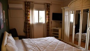 A bedroom with a bed, a TV, and a wardrobe. - AL Mansour Mohammed, very sunny،Amazing terrace (Zamalek)