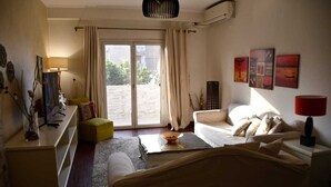 A living room with a sofa, a coffee table, a lamp, and a view through a sliding door to an outdoor area. - AL Mansour Mohammed, very sunny،Amazing terrace (Zamalek)