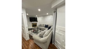 Un salon comprenant un canapé, une table basse et un téléviseur à écran plat fixé au mur.