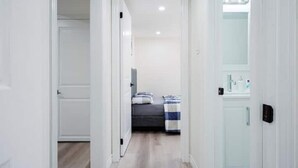 A narrow hallway leading to a bedroom with a bed and a nightstand. - Stylish, Spacious 6-Bedroom Home in the GTA (Whitby)