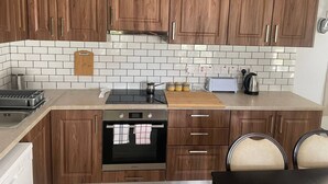 A modern kitchen with wooden cabinets, a black countertop, a built-in oven, a toaster, and a kettle. - Monolithos Cottage in the Troodos Mountains above Limassol (Pachna)