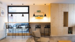 A modern interior with a seating area, a wooden cabinet, and a window with a view of a car outside. - Urban Cube Hostel Granada (Granada)