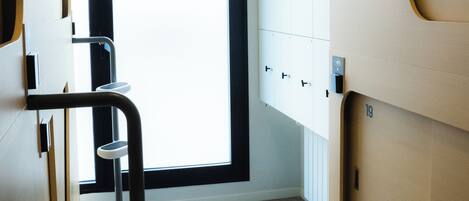 Un baño moderno con un ventanal grande, un tocador con espejo y un inodoro.
