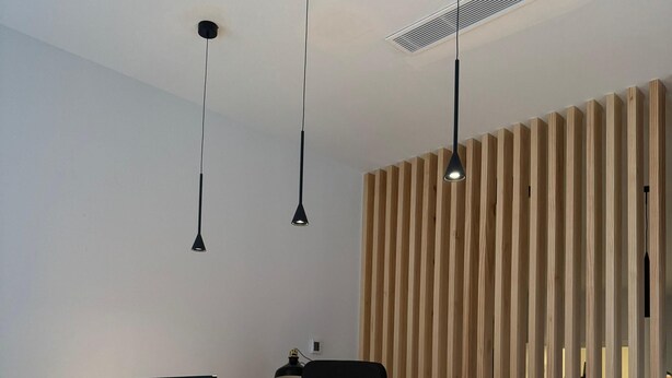 A reception desk with a modern design, featuring a wooden slat wall and a black countertop. - Urban Cube Hostel Granada (Granada)