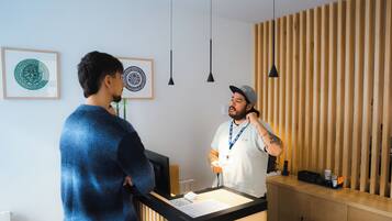 Een receptiebalie met een houten paneelwand, ingelijste kunstwerken en hanglampen.