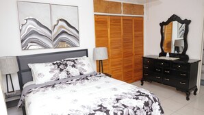 A bedroom with a bed, a dresser, a mirror, and a wardrobe.