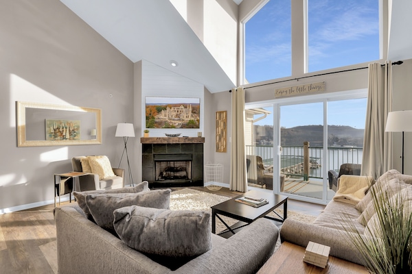 Living area with TV and Fireplace with view of the lake and access to deck.