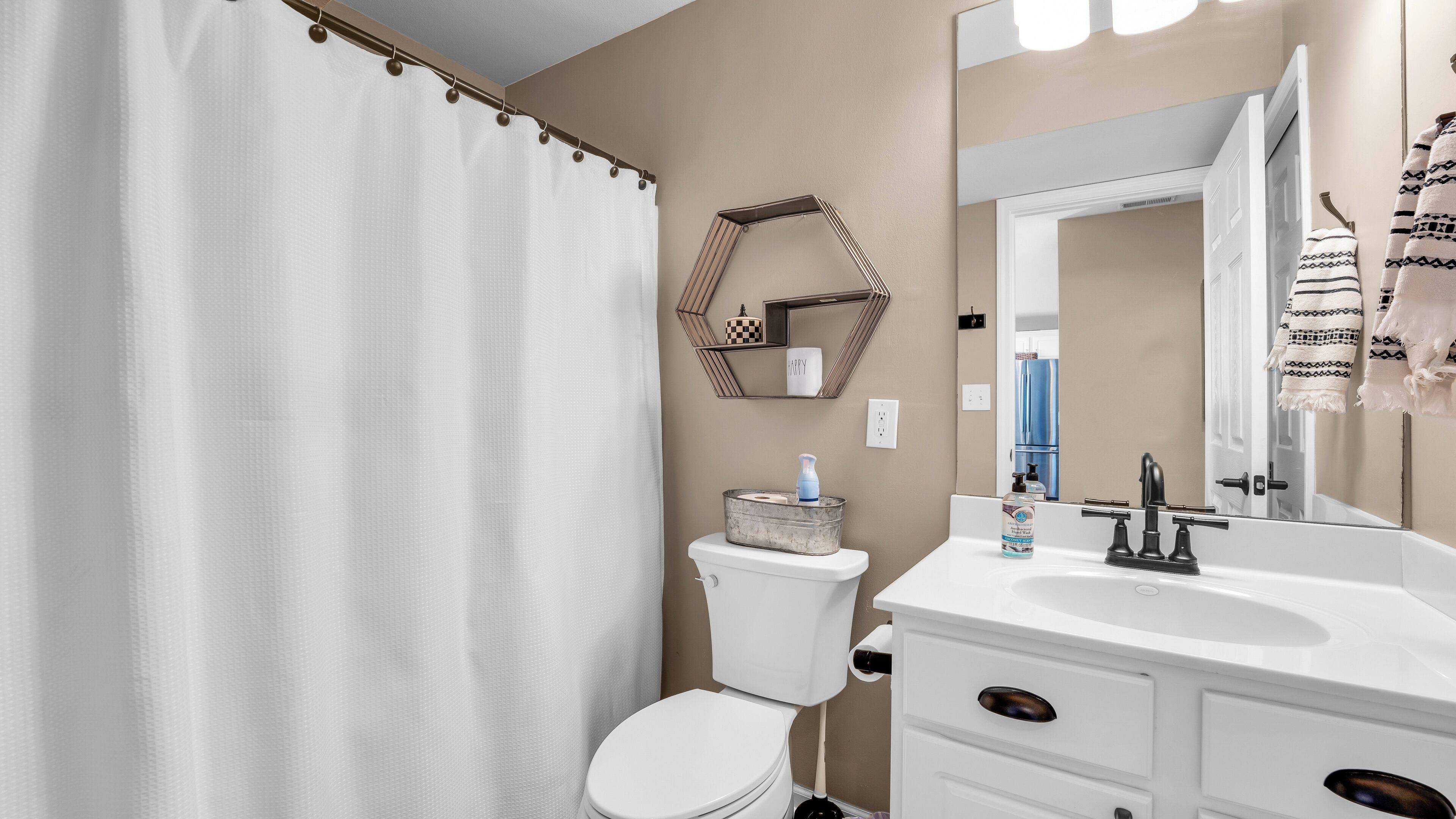 A bathroom with a white toilet, a sink with a mirror, and a shower curtain.