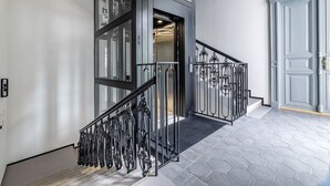 Eine moderne Treppe mit einem schwarzen Metallgeländer und einem geometrisch gemusterten Boden.
