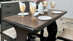 A dining table with a vase of flowers and two wine glasses.