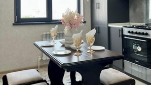 A modern kitchen with a dining area. There is a large window, a stove, and a dining table with chairs.