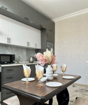 A dining table with a vase of flowers and two wine glasses. - Chaqar 45 (Tashkent)