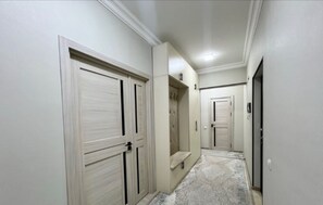 A hallway with closed doors, a bench, and a patterned carpet. - Chaqar 45 (Tashkent)