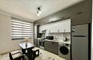 A modern kitchen with grey cabinets, a built-in oven, a microwave, and a refrigerator. - Chaqar 45 (Tashkent)
