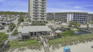 A coastal hotel with a beachside location, a parking area, and a small dock over water. - Myrtle Beach Resort Ocean Spa 351- 2BR-Pool (Myrtle Beach)