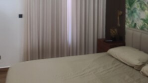 A hotel room with a bed, a nightstand, and a curtain.