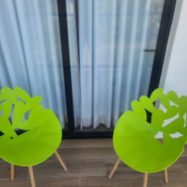 Two green chairs with wooden legs in a room with a wooden floor and a window with curtains. - The Best Suite in DownTown Punta Cana (Punta Cana)