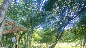 A rustic wooden structure with a bench, a small table, and a hanging light fixture.