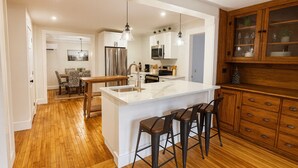 Una cocina moderna con una isla central, taburetes de madera y armarios empotrados de madera.