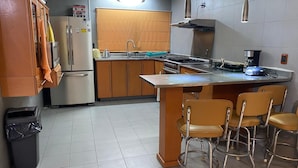 A kitchen with a central island, bar stools, a refrigerator, a stove, and a sink. - Rincon Regio - your stay in San Nicolas (San Nicolás de los Garza)