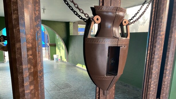 A large, rustic-looking metal urn with chains, placed in a doorway with green walls and tiled floor. - Rincon Regio - your stay in San Nicolas (San Nicolás de los Garza)