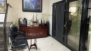 A room with a dining table, chairs, a cabinet with decorative items, a framed cityscape painting, and a large black door with blinds. - Rincon Regio - your stay in San Nicolas (San Nicolás de los Garza)