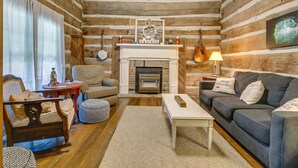 A log cabin interior with a fireplace, sofas, a coffee table, and a guitar.