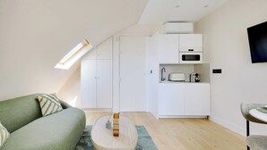 A modern, compact living space with a loft bedroom, kitchenette, and a dining area.