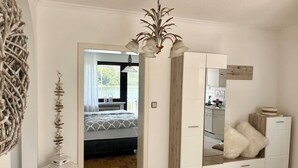 Een slaapkamer met een bed, een kledingkast, een spiegel en een hanglamp.