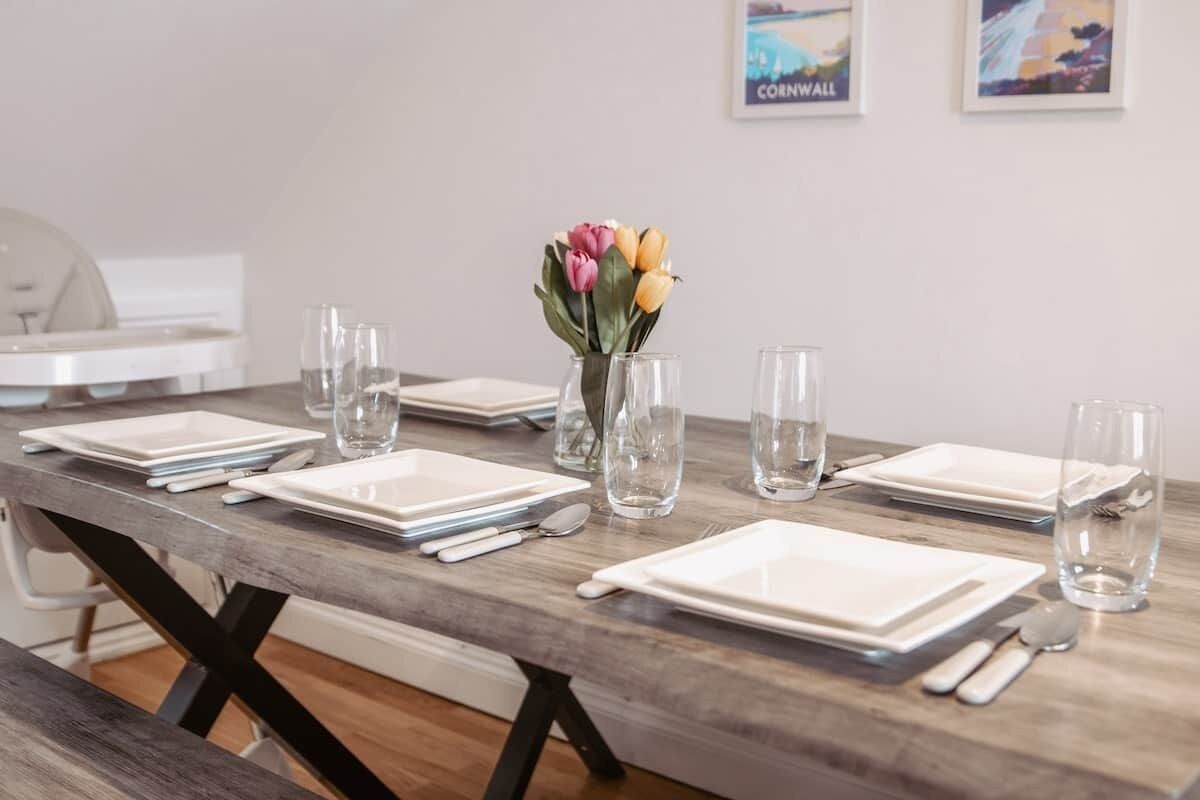 A dining table set with plates, cutlery, and glasses, with a vase of tulips on the table.