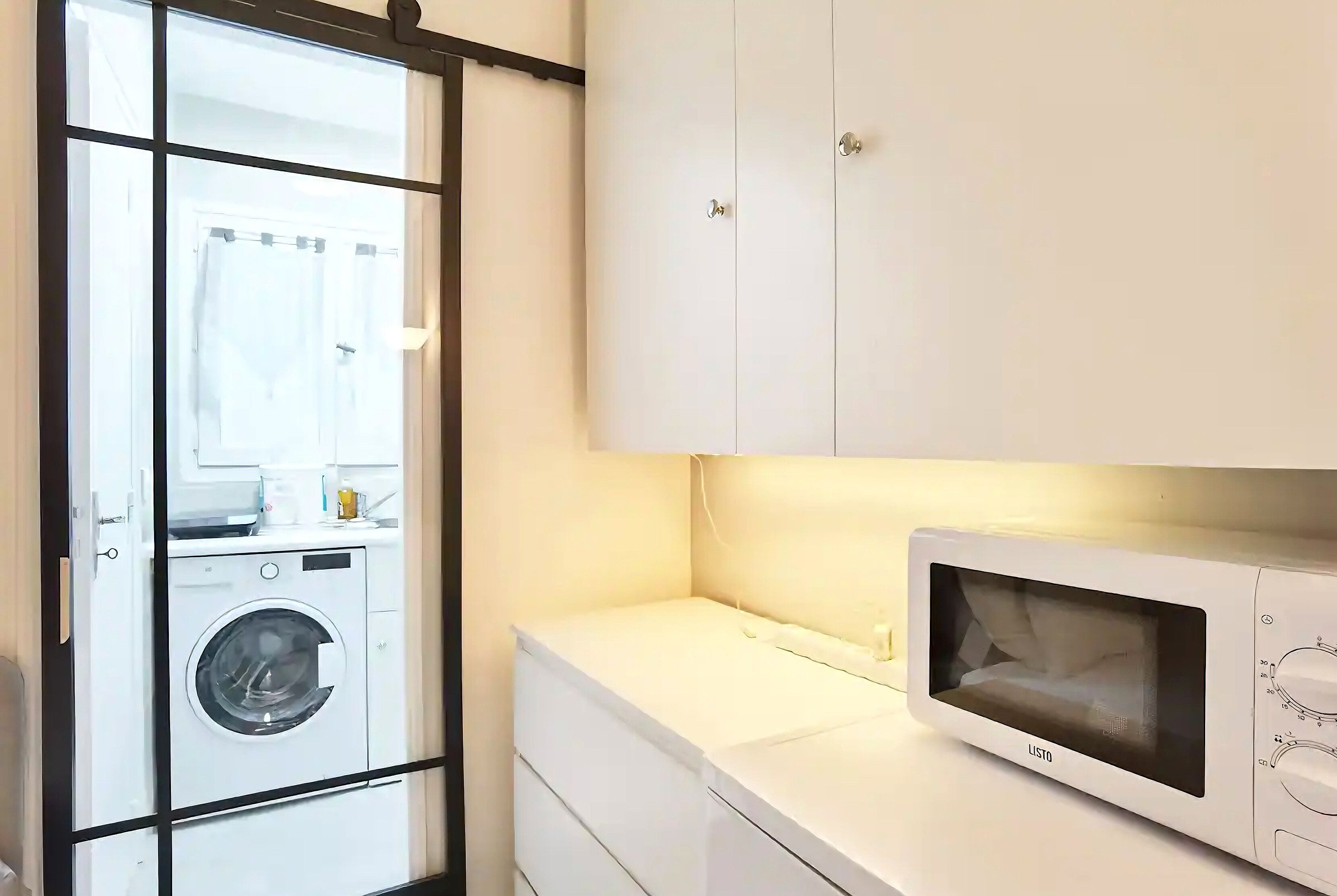 Une buanderie équipée d’un lave-linge, d’un four à micro-ondes et d’un étendoir.