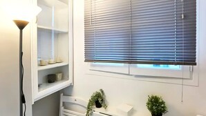 A room with a white cabinet, a hanging plant, and a window with blinds.