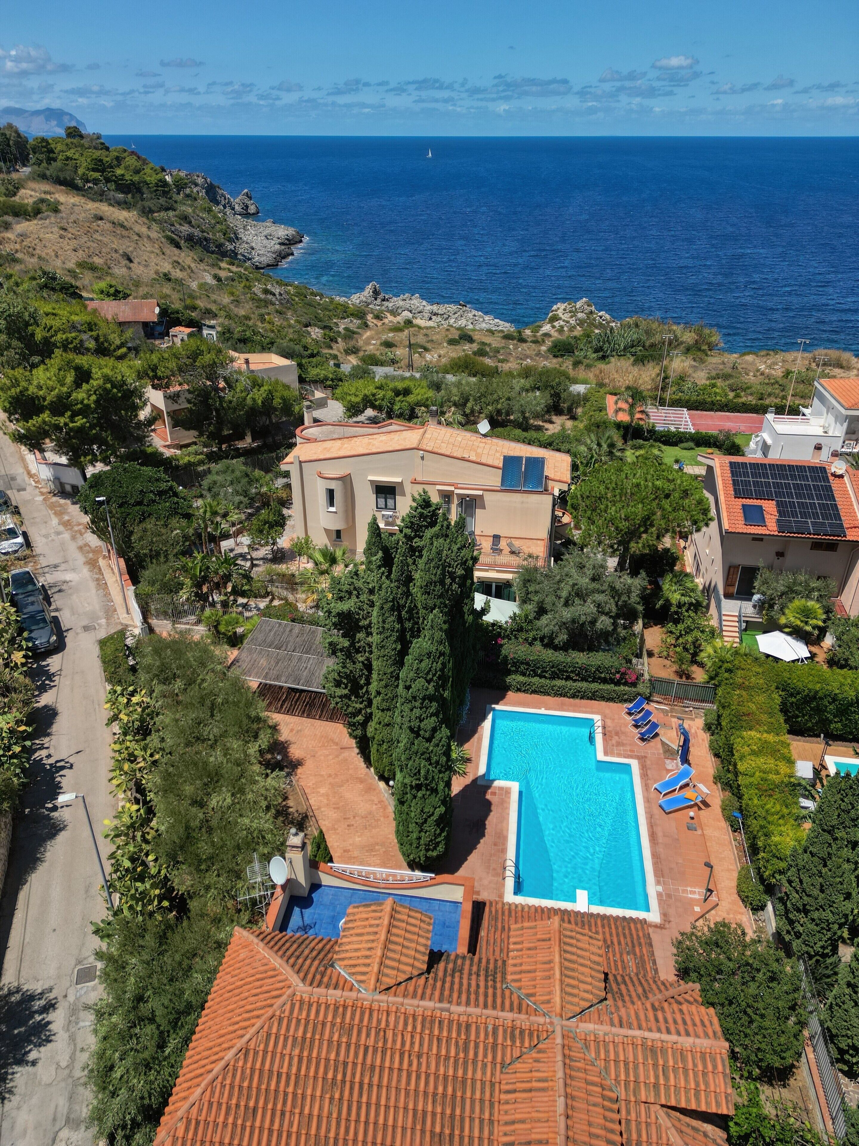 A coastal property with a swimming pool, solar panels, and a view of the sea.