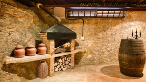 Una pared de piedra rústica con un horno de ladrillo, macetas de terracota y un barril de madera.