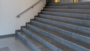 Een trap met een modern ontwerp, met een metalen leuning en een ronde lamp erboven.