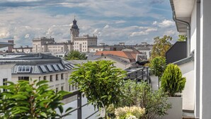 Een houten terras met plantenbakken en uitzicht op stadsgebouwen.