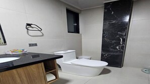 A modern bathroom with a black marble accent wall, a white toilet, and a wooden vanity. - one-bedroom apartment (Cochabamba)