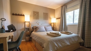Una camera da letto con un letto, lampade ai comodini, una scrivania con una sedia e una finestra con tende.